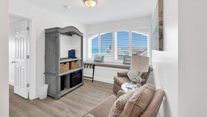 A living room with a sofa, a fireplace, a window with blinds, and a view of the outside. - Beachfront | Pet Friendly | Shared Pool, Elevator (Fort Morgan)