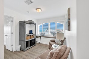 A living room with a sofa, a fireplace, a window with blinds, and a view of the outside. - Beachfront | Pet Friendly | Shared Pool, Elevator (Fort Morgan)