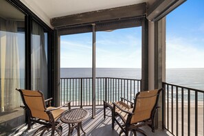 Ein Balkon mit zwei Korbstühlen und einem kleinen Tisch mit Blick auf das Meer.