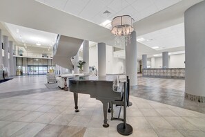 A spacious lobby with a grand piano, a chandelier, and a modern design.