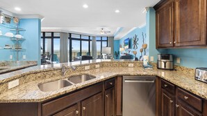 Una cocina moderna con encimeras de granito, electrodomésticos de acero inoxidable y armarios de madera.