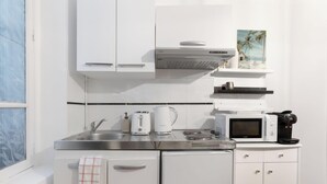 Eine Küche mit weißen Schränken, einer Edelstahl-Spüle, einer Kaffeemaschine, einer Mikrowelle und einem Toaster.
