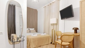 Ein Hotelzimmer mit Bett, Schreibtisch mit Stuhl, Fernseher und Spiegel.