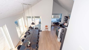 A modern kitchen with a long dining table, black chairs, and pendant lights. - 5 Star Holiday Home in Lemvig (Lemvig)