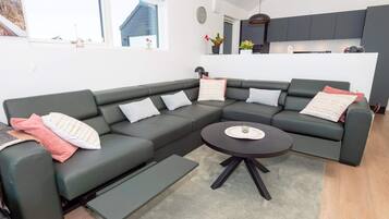 A modern living room with a sectional sofa, a coffee table, and a kitchen in the background.