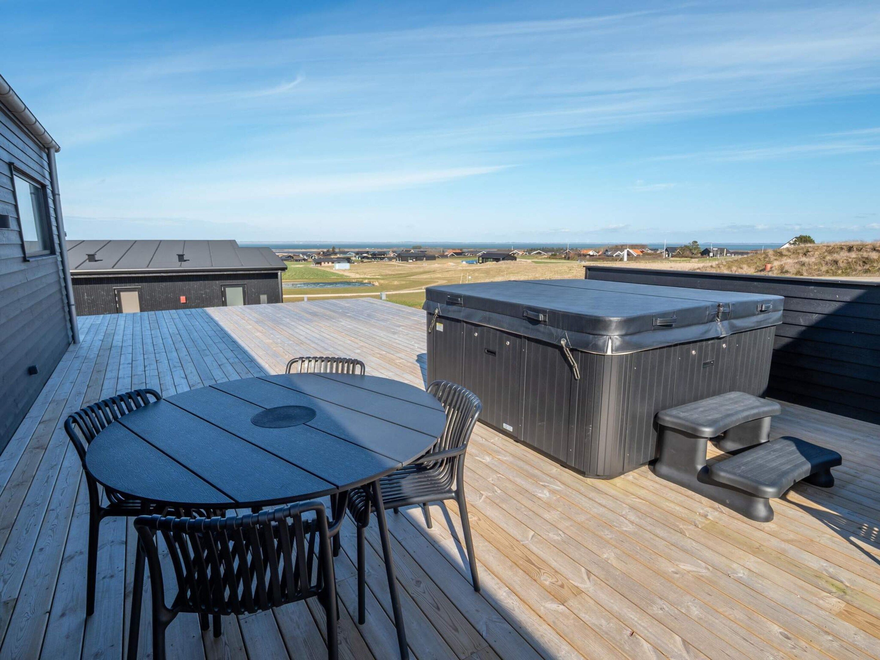 Terraza exterior con mesa y sillas, un jacuzzi y vistas del paisaje.