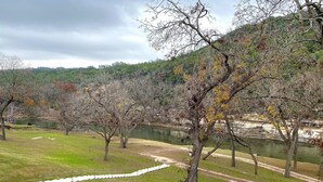 A park with a walking path, trees, and a body of water. - River City Resorts: Rio Guad 313: Remarkable Condo, Guadalupe River View! (New Braunfels)