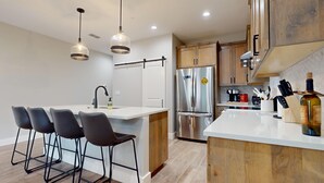 A modern kitchen with a central island, stainless steel appliances, and bar stools. - River City Resorts: Rio Guad 313: Remarkable Condo, Guadalupe River View! (New Braunfels)
