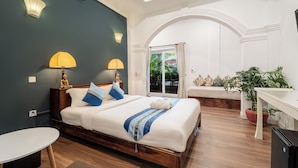 Een slaapkamer met een bed, nachtlampjes, een klein tafeltje, een bloempot en uitzicht op het landschap.