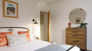 Una camera da letto con un letto, una cassettiera, uno specchio e una mappa incorniciata appesa al muro.