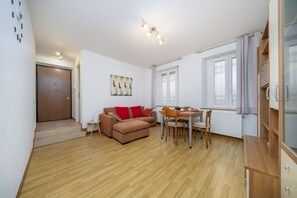 Un espacio habitable compacto con sofá, mesa de comedor, sillas y un armario.