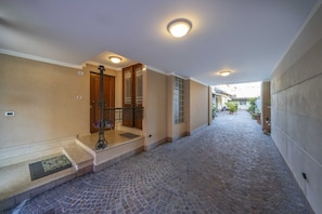 Un pasillo con piso de piedra, una puerta de madera y una reja de metal.