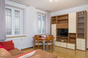 A compact living space with a dining table, chairs, a sofa, a TV, and built-in shelving. - GuestHost - Comfortable 69 sqm apartment, perfect for groups or families of up to 4 guests, located on the ground floor of a historic building (a few steps to access).The apartment is located just outside the centre of Udine, a perfect alternative for th (Udine)