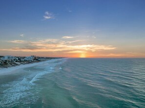 A coastal view with a sunset, a beach, and a row of houses along the shore. - Runaway to 30A- Walk to beach, neighborhood pool! (Santa Rosa Beach)