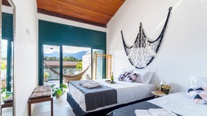 A hotel room with two beds, a hammock, a view of mountains, and a balcony with a chair. - Piscina e AC na Praia do Una (Sao Sebastiao)
