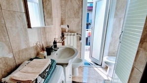 Une salle de bain avec un lavabo, un miroir et des toilettes. On y trouve un porte-serviettes avec des serviettes pliées.