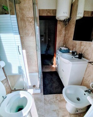 A bathroom with a toilet, bidet, washing machine, and a shower area. - Milan shopping street house (Milano)