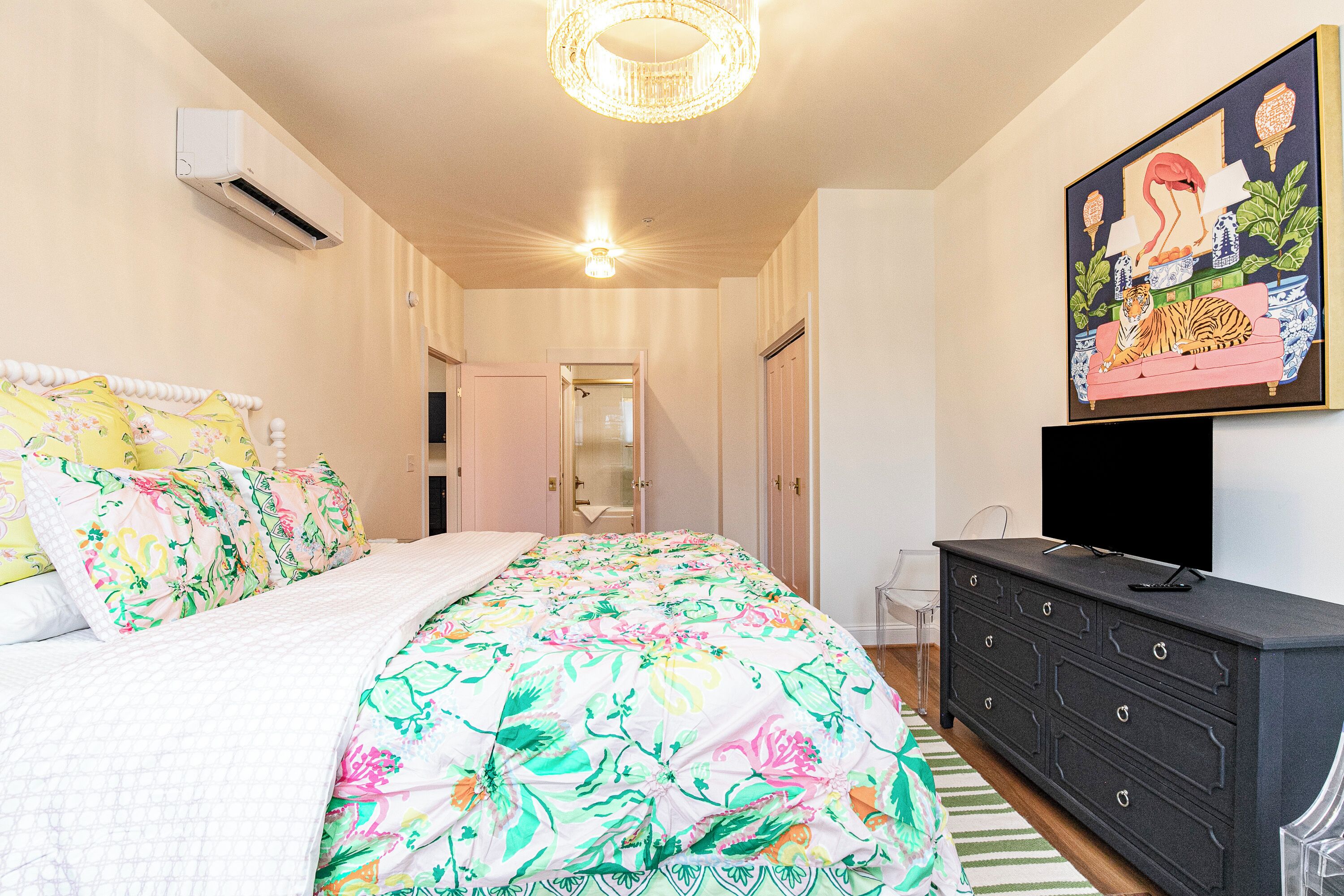 A bedroom with a bed, dresser, and a painting on the wall.