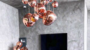 A modern living room with a large flat-screen TV, orange leather sofas, and copper spherical light fixtures. - Comfy Studio in Gudauri Marshall - By Wehost (Gudauri)