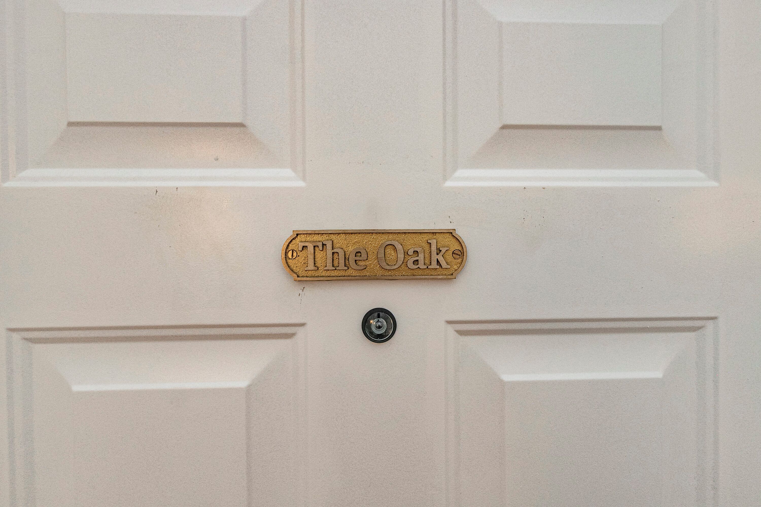 Eine weiße Tür mit einer Messingschild, auf dem „The Oak“ steht.