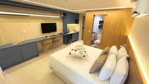 Une chambre d’hôtel moderne équipée d’un lit, d’une table de chevet, d’un bureau, de chaises et d’un téléviseur.