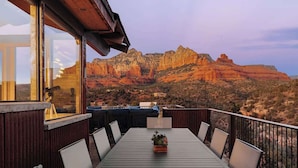 Um terraço com mesa e cadeiras, com vista para uma paisagem montanhosa.