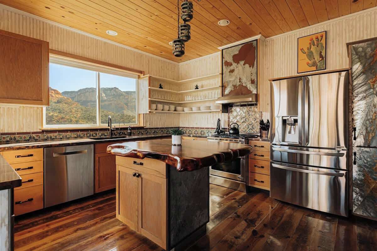 Una cocina con armarios de madera, un refrigerador de acero inoxidable y una isla grande con encimera.