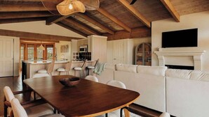 A spacious living area with a wooden dining table, white sofa, and a fireplace. - A Sedona Scenic Escape w/ Private Wellness Center (Sedona)