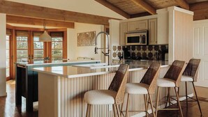 A kitchen with wooden beams, a central island with stools, and a microwave. - A Sedona Scenic Escape w/ Private Wellness Center (Sedona)