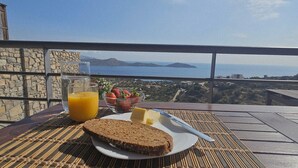 Et bord med mad, et glas appelsinjuice og en skål jordbær på en balkon med udsigt over et smukt landskab.