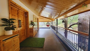 A wooden corridor with a hanging chair, a potted plant, and a view of the outdoors. - La Cedar Villa by Staycation (Manali)
