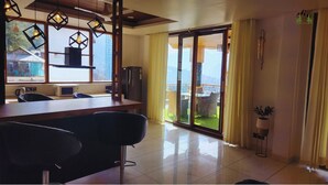 A modern kitchen with a bar area, large windows, and a view of the outdoors. - La Cedar Villa by Staycation (Manali)