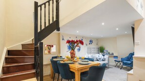Un comedor con una mesa de madera, sillas azules y un jarrón de flores rojas.