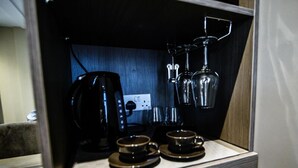 A compact kitchenette with a coffee maker, two cups, and a wine glass rack. - Ladywell House (Birmingham)