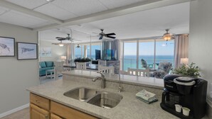 Een moderne keuken met een groot eiland, een koffiezetapparaat en uitzicht op zee.