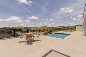 A rooftop pool area with a view of the countryside, a table with chairs, and a glass balustrade. - Casa Alto Padr o com Piscina Sauna e Vista (São José dos Campos)