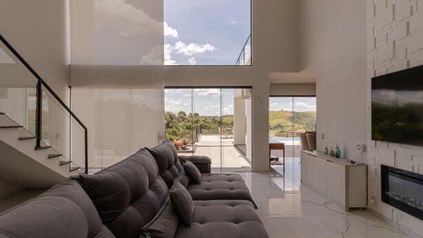 A modern living room with a large sectional sofa, a flat-screen TV mounted on the wall, and a fireplace.