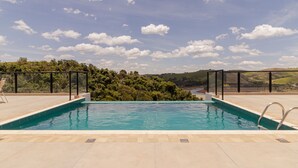 A swimming pool with a view of a river and hills.