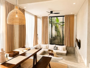 A modern living room with a dining area, a ceiling fan, and a large window with curtains. - Industrial Style 2 Bedroom Villa with Private Pool in Pererenan (Badung Regency)