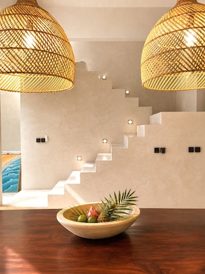 A staircase with integrated lighting, a bowl of fruit on a wooden table, and two hanging wicker lamps. - Industrial Style 2 Bedroom Villa with Private Pool in Pererenan (Badung Regency)