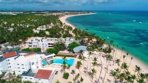 Un complejo turístico frente al mar con piscina, villas en la playa y acceso directo a la costa.