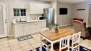 A compact kitchen with white cabinets, a stainless steel refrigerator, and a microwave on the counter.