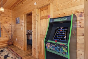A wooden interior with a retro arcade machine labeled 'Mortal'. - Honey Bear Lodge, 4BR Family Cabin, Hot Tub, Views, Seasonal Resort Pool (Gatlinburg)