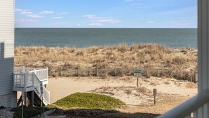 A beach view with a wooden fence, a small grassy area, and a building with a balcony. - A Place in the Sun 301 by seaside Vacations & Sales (Ocean City)