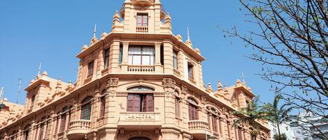 Un edificio histórico con arquitectura ornamentada, varios balcones y grandes ventanales.