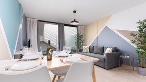 Ein modernes Wohnzimmer mit Essbereich, einem grauen Sofa und einem Blumentopf.