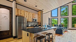 Una cucina moderna con mobili in legno, elettrodomestici in acciaio inossidabile e una grande isola con sgabelli da bar.