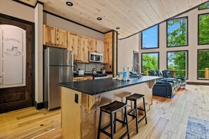 A modern kitchen with wooden cabinets, stainless steel appliances, and a large island with bar stools. - Nestled in the heart of Gatlinburg, "Waterfalls and Wildflowers" offers a serene (Gatlinburg)