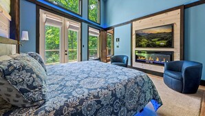 Una camera da letto con un letto grande, un camino e vista sul verde.