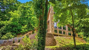 A stone tower structure with a wooden staircase leading up to a building surrounded by lush greenery. - Nestled in the heart of Gatlinburg, "Waterfalls and Wildflowers" offers a serene (Gatlinburg)